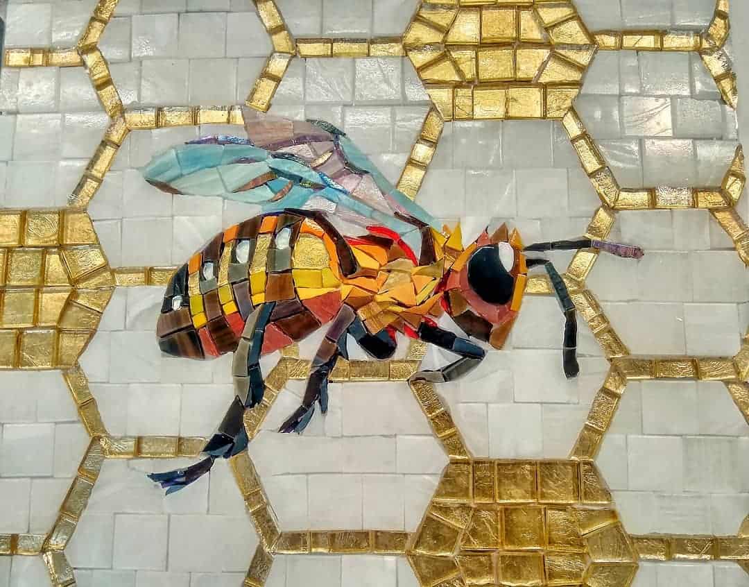 A colorful mosaic of a honey bee set against a background of hexagonal tiles, resembling a honeycomb