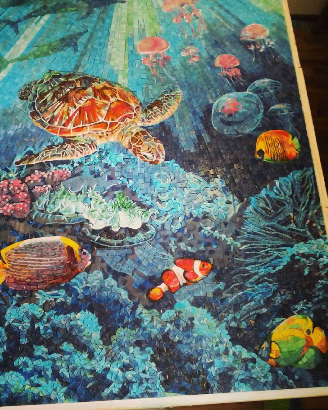 A colorful underwater scene depicted in a mosaic style, featuring a sea turtle, various fish, and coral reefs

