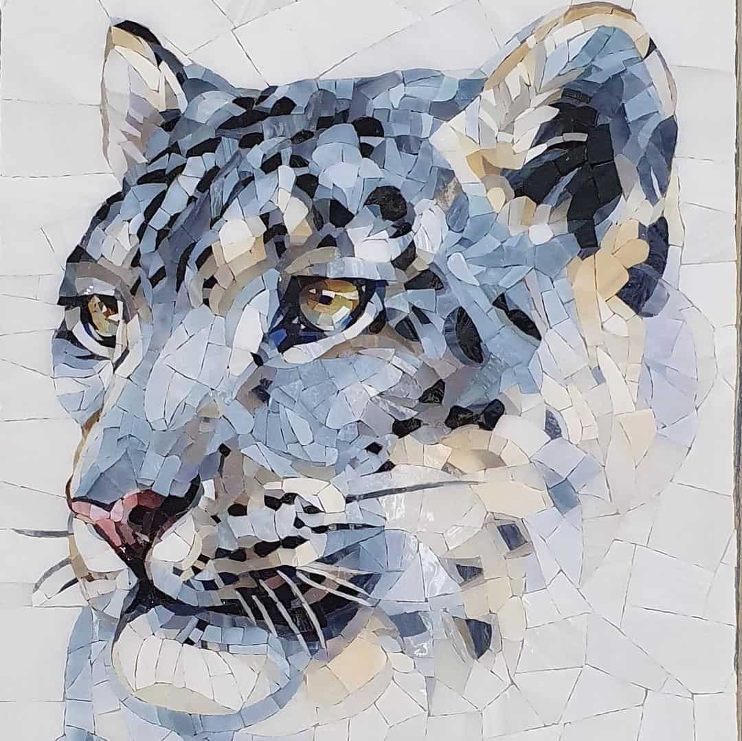 A mosaic art piece depicting a snow leopard with various shades of blue, grey, and white tiles